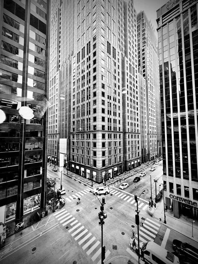 Black and white view down on a city intersection between tall office towers